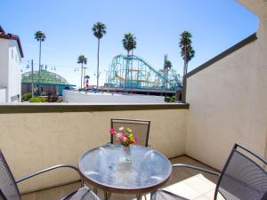 a table with flowers on a balcony with a roller coaster at Carousel Beach Inn in Santa Cruz