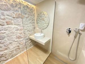 a bathroom with a shower with a sink and a mirror at 70 sqm sea view apartment in Parga +11 photos