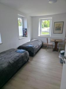 a room with two beds and a table and two windows at My Pension City Großaitingen - Augsburg in Großaitingen
