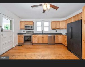 a kitchen with wooden cabinets and a ceiling fan at Need a room i got you in Frederick