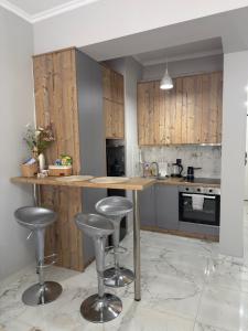 a kitchen with wooden cabinets and bar stools at Eleni’s Mountainview Central Studio by the Sea in Loutraki