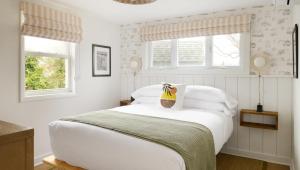a white bedroom with a bed with a yellow bag on it at The Penny Lane in Hampton Bays