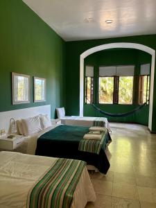 a green bedroom with two beds and a mirror at Pousada Casa Imperatriz - Rua Teresa in Petrópolis