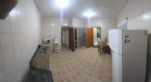 a kitchen with a refrigerator and a table in it at Acomodação Recanto do Sameiro in Mongaguá
