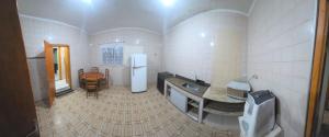 a kitchen with a sink and a refrigerator and a table at Acomodação Recanto do Sameiro in Mongaguá +21 photos