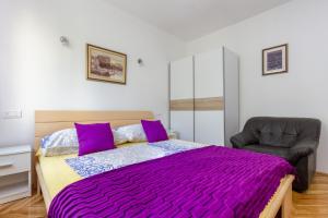 a bedroom with a bed with purple sheets and a chair at Belvedere Apartment in Split