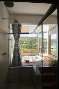 a bathroom with a tub and a large window at Chalé Jenipapo in Serra do Cipo