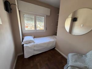 a small bedroom with a bed and a mirror at Hospedajes Edén in La Falda