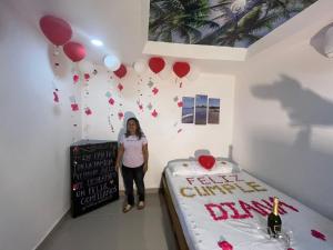 a woman standing next to a birthday cake with balloons at Hotel Y Restaurante Verano Azul in Moñitos