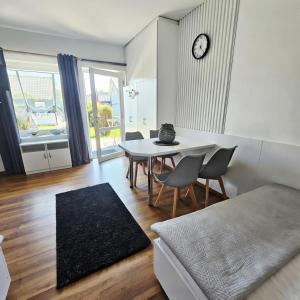 a living room with a table and chairs and a clock at Fox pokoje-apartament-domki in Władysławowo