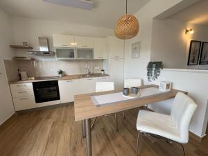 a kitchen with a wooden table and white chairs at Studio Apartman Nika in Višnjan