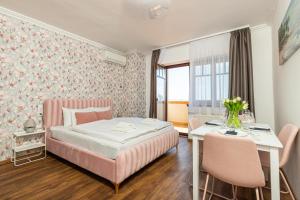 a bedroom with a pink bed and a table and chairs at Olgi Milla Villa in Balatonalmádi