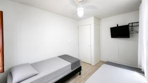 a bedroom with a bed and a flat screen tv at Sossai Hostel in Vitória
