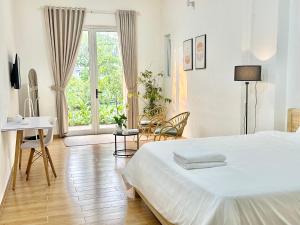 a bedroom with a bed and a desk and a window at Villa Rosa HueS in Thôn An Hòa