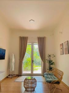 a living room with a large window and a chair at Villa Rosa HueS in Thôn An Hòa
