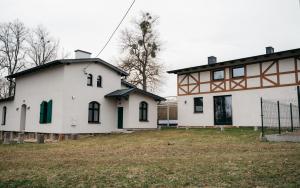 a white house with green windows and a building at Folwark Karczemka in Małdyty