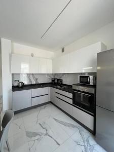 a kitchen with white cabinets and black appliances at Appartamenti Gemma in Calmasino