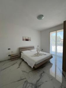 a white bedroom with a bed and a large window at Appartamenti Gemma in Calmasino