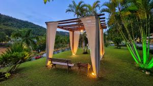 a gazebo in a park with a bench and lights at Flat 113, Hotel Cavalinho Branco in Águas de Lindoia