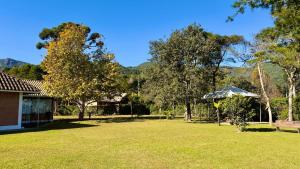 a park with a bench and an umbrella and trees at Pousada Villa do Luar by Concavus in Monte Verde