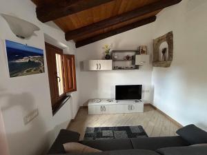 a living room with a couch and a tv at Casa Verde con servizio gratuito E-Bike in Seneghe