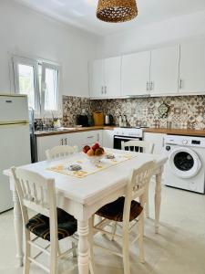 a white kitchen with a white table and chairs at Serenity in Petra