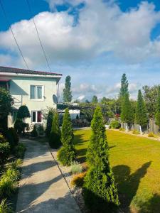a house with a yard with trees and a sidewalk at Guesthouse FLORA ANAKLIA in Anaklia
