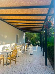 a patio with white tables and chairs under awning at Guesthouse FLORA ANAKLIA in Anaklia