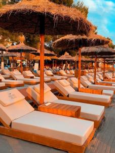 a row of lounge chairs with umbrellas on a beach at Dublex Friendly apartaments perball Rafaelos in Shëngjin