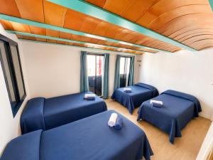 a room with three blue beds and windows at La Esquineta de Tabarca in Tabarca