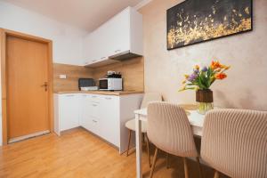 a kitchen and a table with chairs and a vase of flowers at Guesthouse Rebecca in Makarska