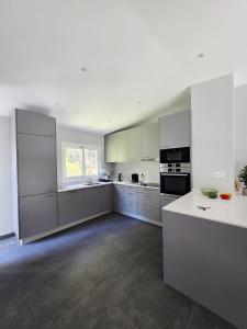a large white kitchen with white cabinets and appliances at Duplex Residence with Monte Carlo Sea View & 2 Terraces in Roquebrune-Cap-Martin