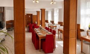 a dining room with a long table and red chairs at Hotel Casanova in Duchcov