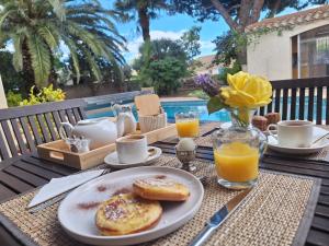 a table with a plate of breakfast food and orange juice at Villa Pesona in Vias