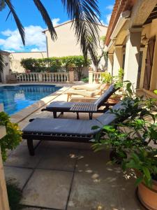 a pool with two lounge chairs next to a house at Villa Pesona in Vias +16 photos