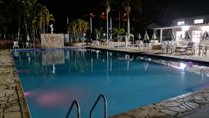 a swimming pool at night with tables and chairs at Flat 113, Hotel Cavalinho Branco in Águas de Lindoia