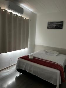 a white room with a bed and a window at HL Hotel in Pelotas