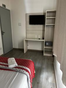 a bedroom with a bed and a desk with a television at HL Hotel in Pelotas +1 photo