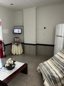 a room with a bed and a table and a tv at HL Hotel in Pelotas