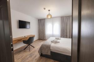 a hotel room with a bed and a desk at Pensiunea Seraris in Voineasa