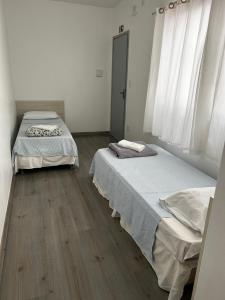 two beds in a room with wooden floors and windows at HL Hotel in Pelotas
