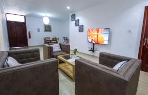 a living room with two couches and a tv at American Mall apartment, Osu in Accra