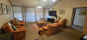 a living room with three chairs and a television at Applegate lodge in Clarens