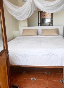 a bedroom with a bed with white sheets and curtains at Beachfront - Private Floor, 4 Rooms - Casa 3 Lunas in Playa Agua Blanca