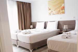 two beds in a hotel room with towels on them at Bebis Rooms in Orikum