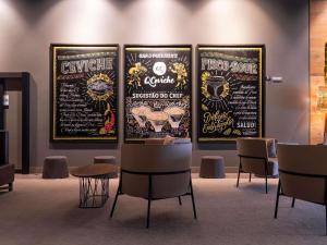three posters on a wall in a room with chairs at Novotel Curitiba Batel in Curitiba +191 photos