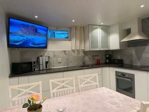 a kitchen with a flat screen tv on the wall at RYMLIG RENOVERAD GÄSTBOSTAD med egen ingång nära stranden i HÄLLEVIK in Sölvesborg