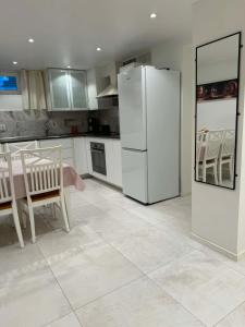 a kitchen with a white refrigerator and a table and chairs at RYMLIG RENOVERAD GÄSTBOSTAD med egen ingång nära stranden i HÄLLEVIK in Sölvesborg
