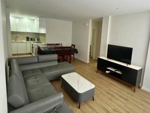 a living room with a couch and a tv and a kitchen at JLKM Mindelo Central Residence in Mindelo