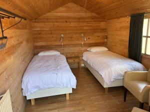 two beds in a room with wooden walls at Summerhouse Torfalundur in Blönduós